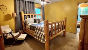 Une chambre à coucher avec un lit en bois, une chaise, une lampe et un ventilateur de plafond.
