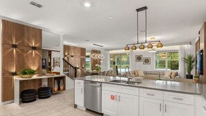 Une cuisine moderne dotée d’un grand îlot central, d’appareils électroménagers en acier inoxydable et d’un mur d’accent en bois.