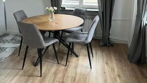 Un coin repas avec une table ronde, six chaises et un vase rempli de fleurs.