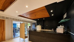 A modern reception area with a dark counter, wooden ceiling, and tiled flooring. - Tetris Container Hostel (Foz do Iguaçu)