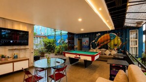A pool table, a sofa, a television, and a dining area with chairs. - Tetris Container Hostel (Foz do Iguaçu)