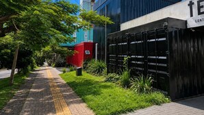 A pathway leading to a building with a modern facade, a gated entrance, and a clear sky. - Tetris Container Hostel (Foz do Iguaçu)