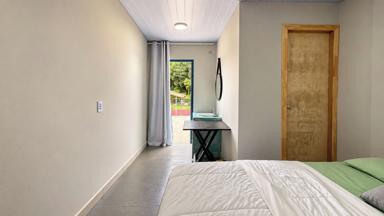 A bedroom with a bed, a desk, and a door.