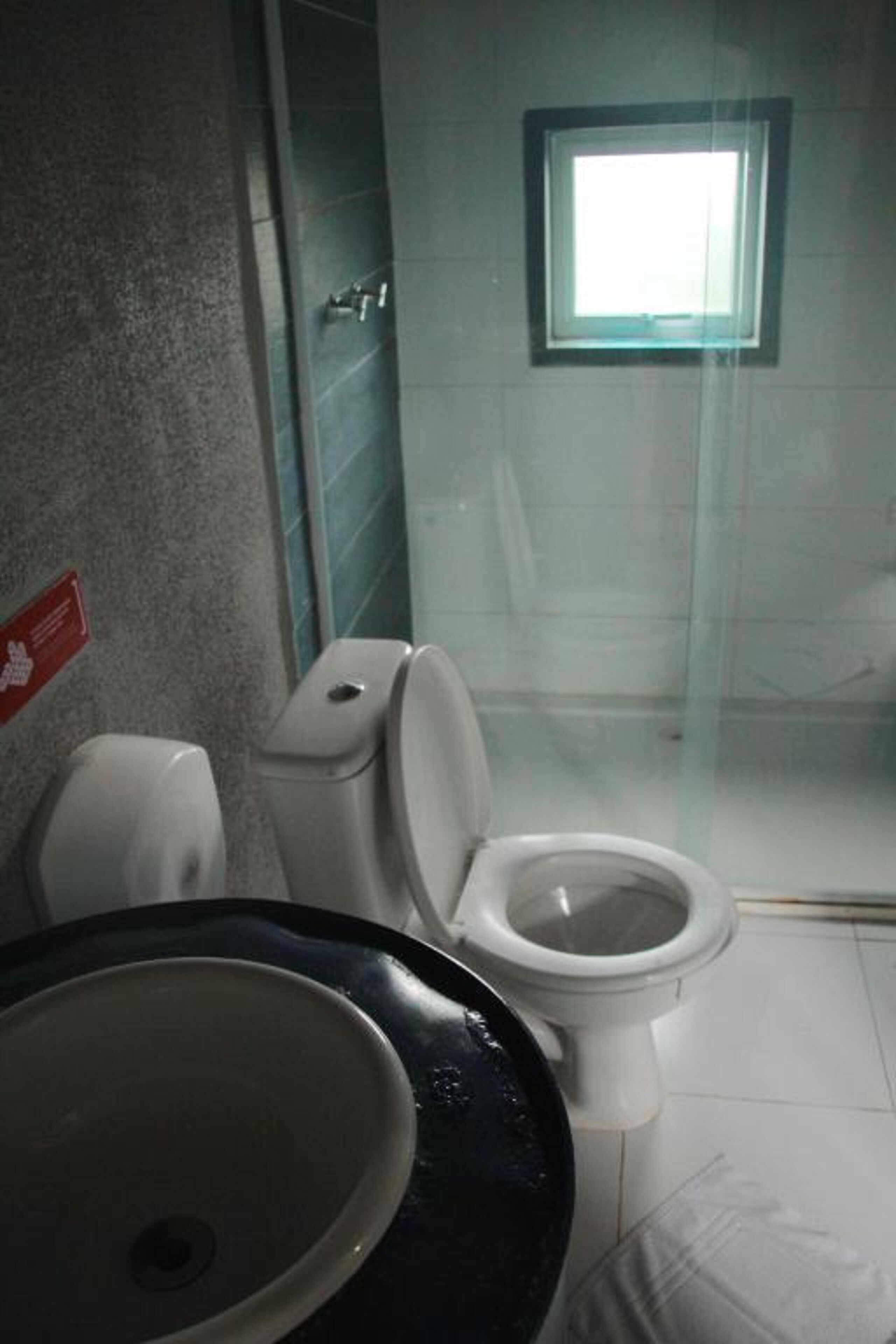 A bathroom with a toilet, sink, and a glass shower enclosure.