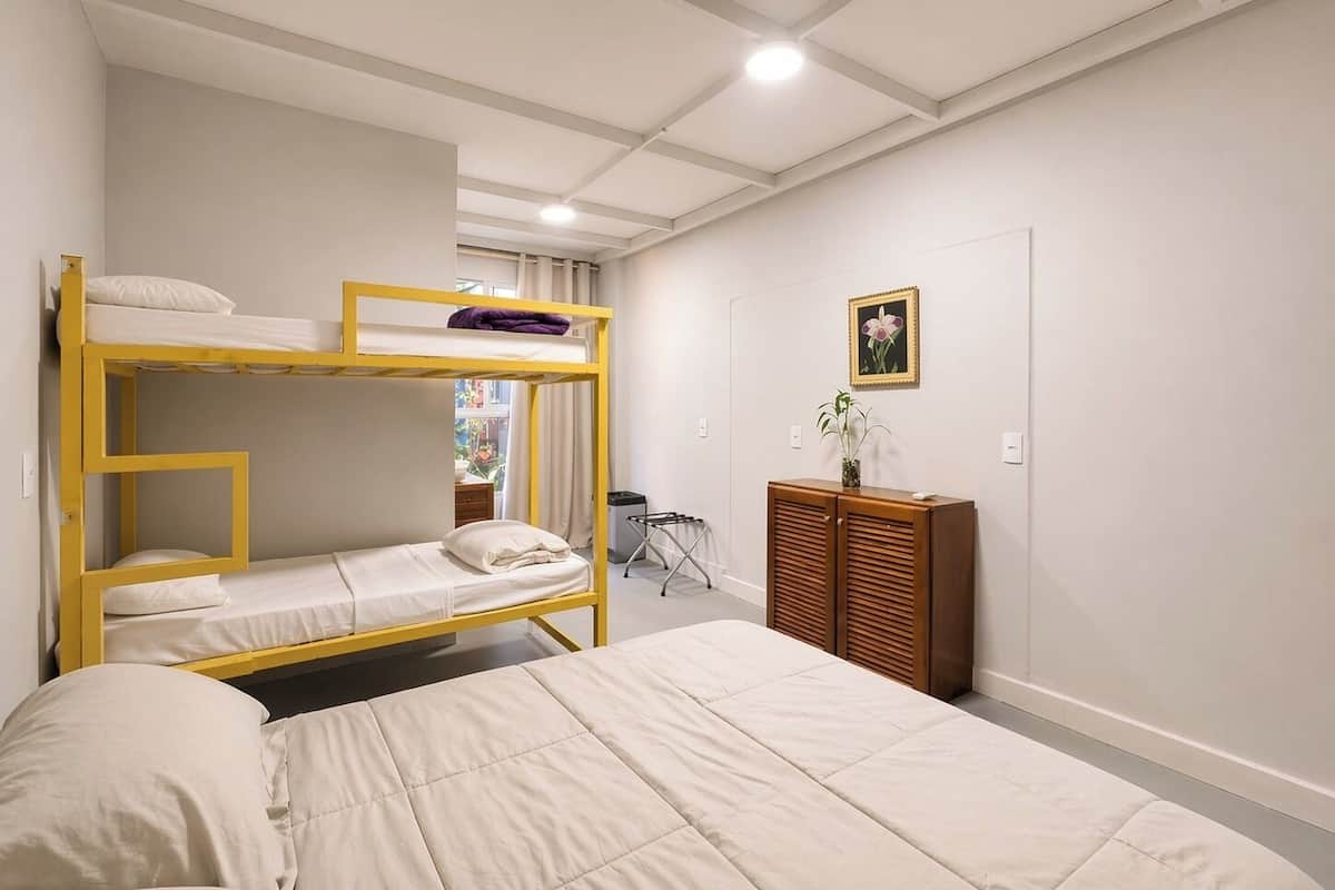 A room with bunk beds, a small cabinet, a chair, and a door.
