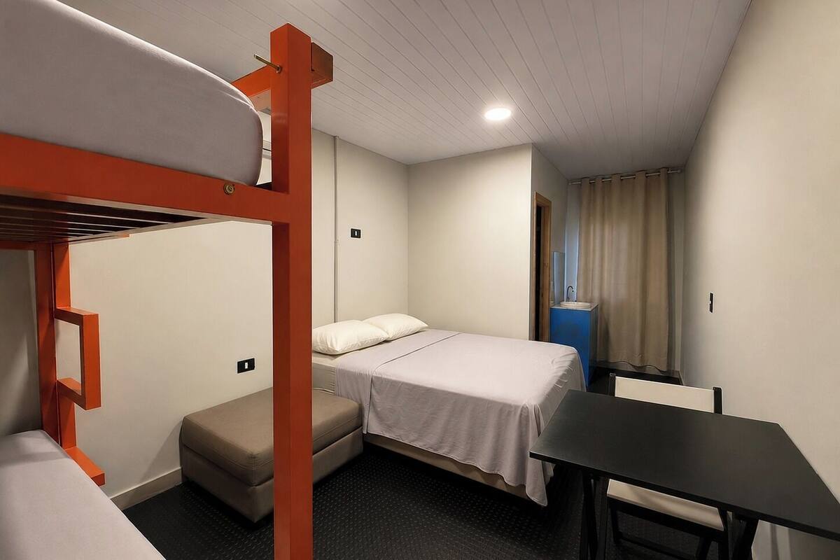 A bunk bed room with a small table and a bench.