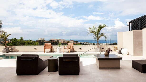Terraza en la azotea con piscina, sillones de descanso y vistas al océano.
