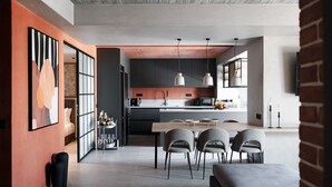 Una cocina moderna con comedor, que incluye una isla grande, luces colgantes y una pared decorativa de ladrillo.