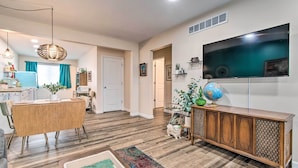 Un salon moderne avec une table à manger en bois, un téléviseur fixé au mur et un globe terrestre posé sur un meuble.