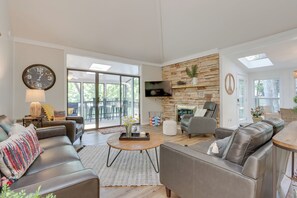 A modern living room with leather sofas, a round coffee table, and a stone accent wall. - Spacious Decks & Dock: Margaritaville Home! (Osage Beach)