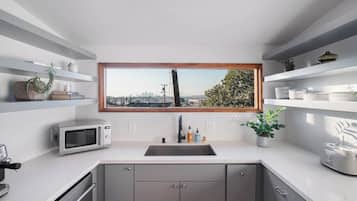 Une cuisine moderne équipée d’un four à micro-ondes encastré, d’un évier et d’une fenêtre donnant sur la ville.