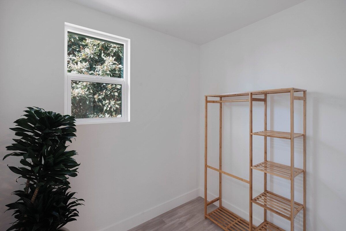 Une pièce avec une fenêtre, une étagère en bois et une plante en pot.