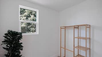 Une pièce avec une fenêtre, une étagère en bois et une plante en pot.