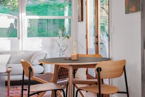 Een eetruimte met een ronde tafel, houten stoelen en uitzicht op groen.