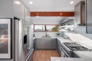 Eine moderne Küche mit Backofen, einem Edelstahl-Kühlschrank und einem Fenster über der Spüle.
