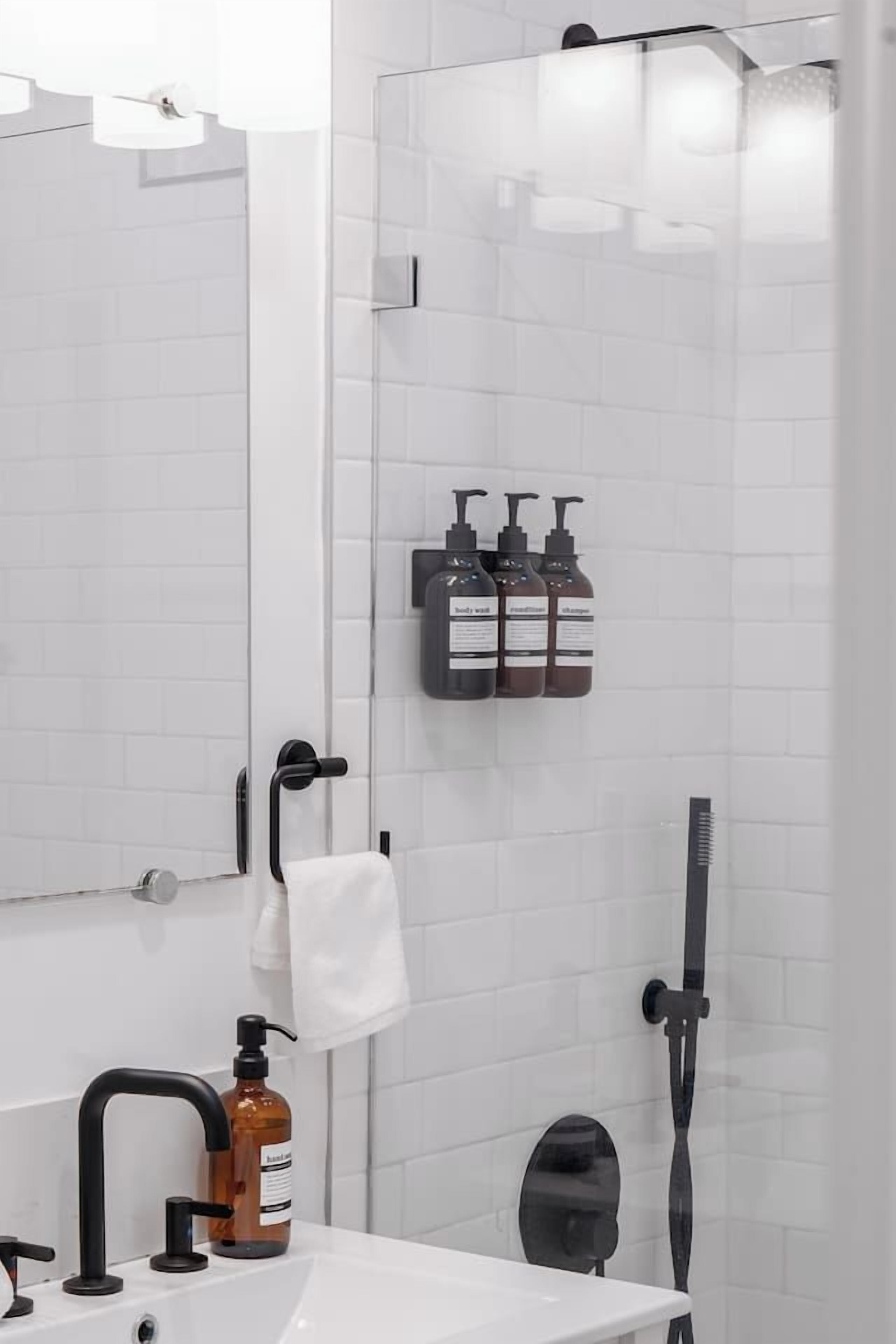 Casa de banho moderna com uma pia branca, chuveiro manual e suporte para toalhas.