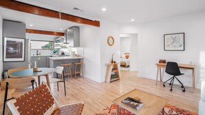 Un salon moderne comprenant un coin repas, une cuisine et un petit espace bureau.