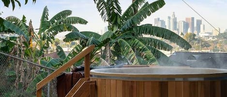 A wooden deck with a hot tub, metal chairs, and a table.