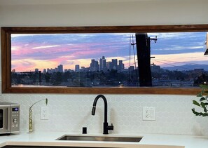 A kitchen with a view of a city skyline at sunset, a modern faucet, and a microwave.