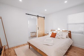 A modern bedroom with a wooden bed, a sliding door, and a bedside table with a lamp.