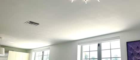 A modern living room with a unique ceiling light fixture, large windows, and contemporary furniture.