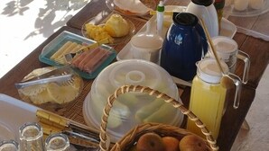 Desayuno con diferentes alimentos y bebidas sobre una mesa al aire libre, cerca de una piscina.