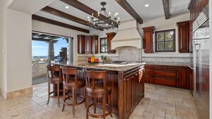 A spacious kitchen with a large island, wooden bar stools, and a built-in stove.