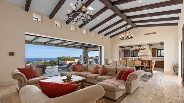 A spacious living area with a large sofa set, a coffee table, and a view of the ocean.
