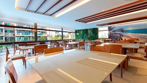 Un restaurante moderno con mobiliario de madera, ventanas amplias y vista al océano.