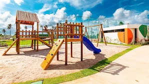 Un parque infantil con una estructura para escalar, toboganes y una zona delimitada por vallas.