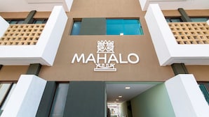 Un edificio con un llamativo letrero que dice 'MAHALO' y un diseño arquitectónico moderno.