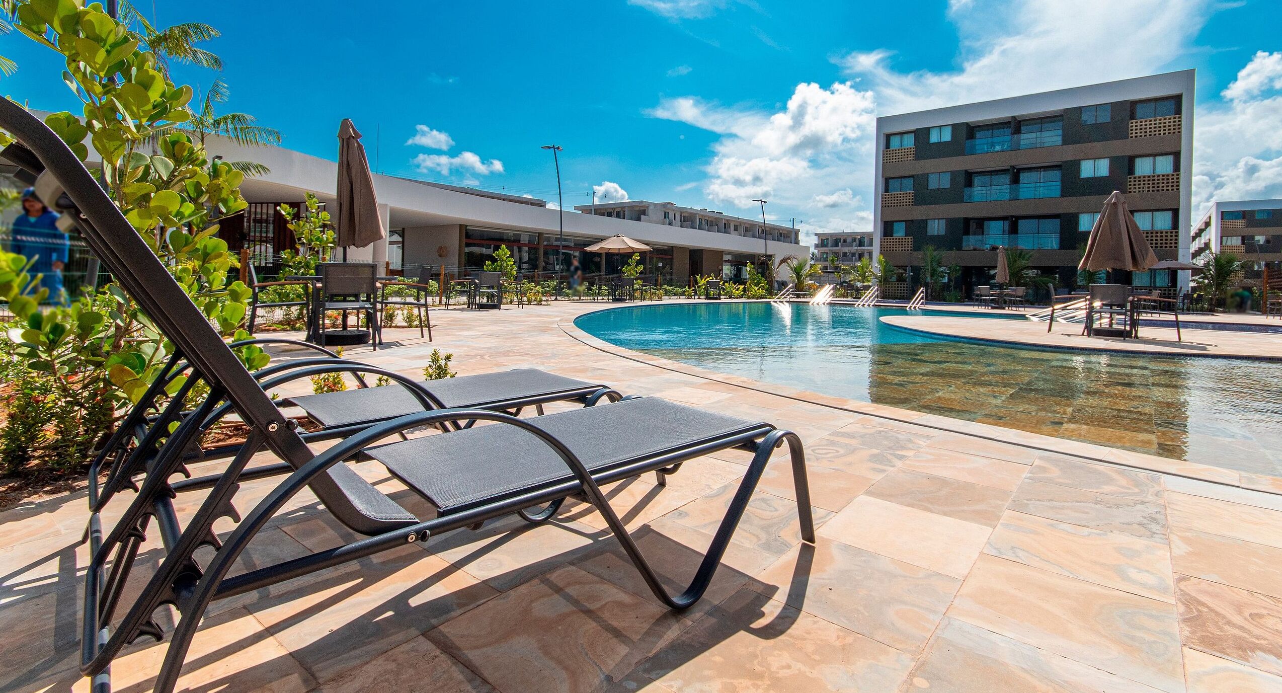 A pool area with lounge chairs and a building in the background.