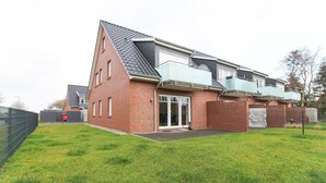 A modern two-story house with a brick facade, large sliding glass doors, and a sloped roof. - Bright, modern ground floor apartment for 4 people including four-legged friends (Norden)