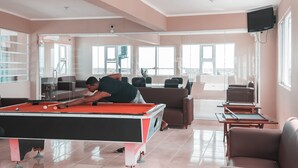 A pool table in a modern living room with a view of the city. - Apartahotel Dubai (Punta Cana)