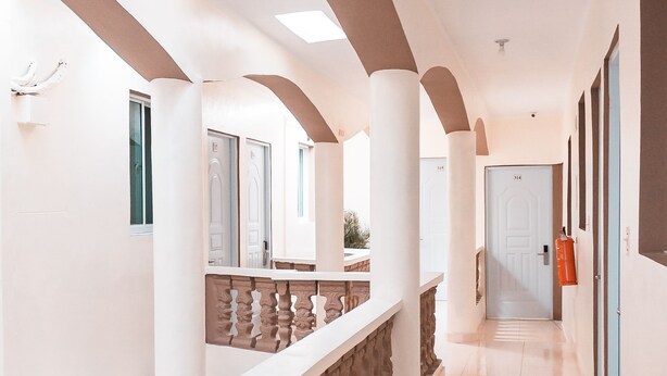 A corridor with white walls, arched ceilings, and a stone balustrade. - Apartahotel Dubai (Punta Cana)