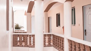 A corridor with white walls, beige columns, and a patterned floor. - Apartahotel Dubai (Punta Cana)