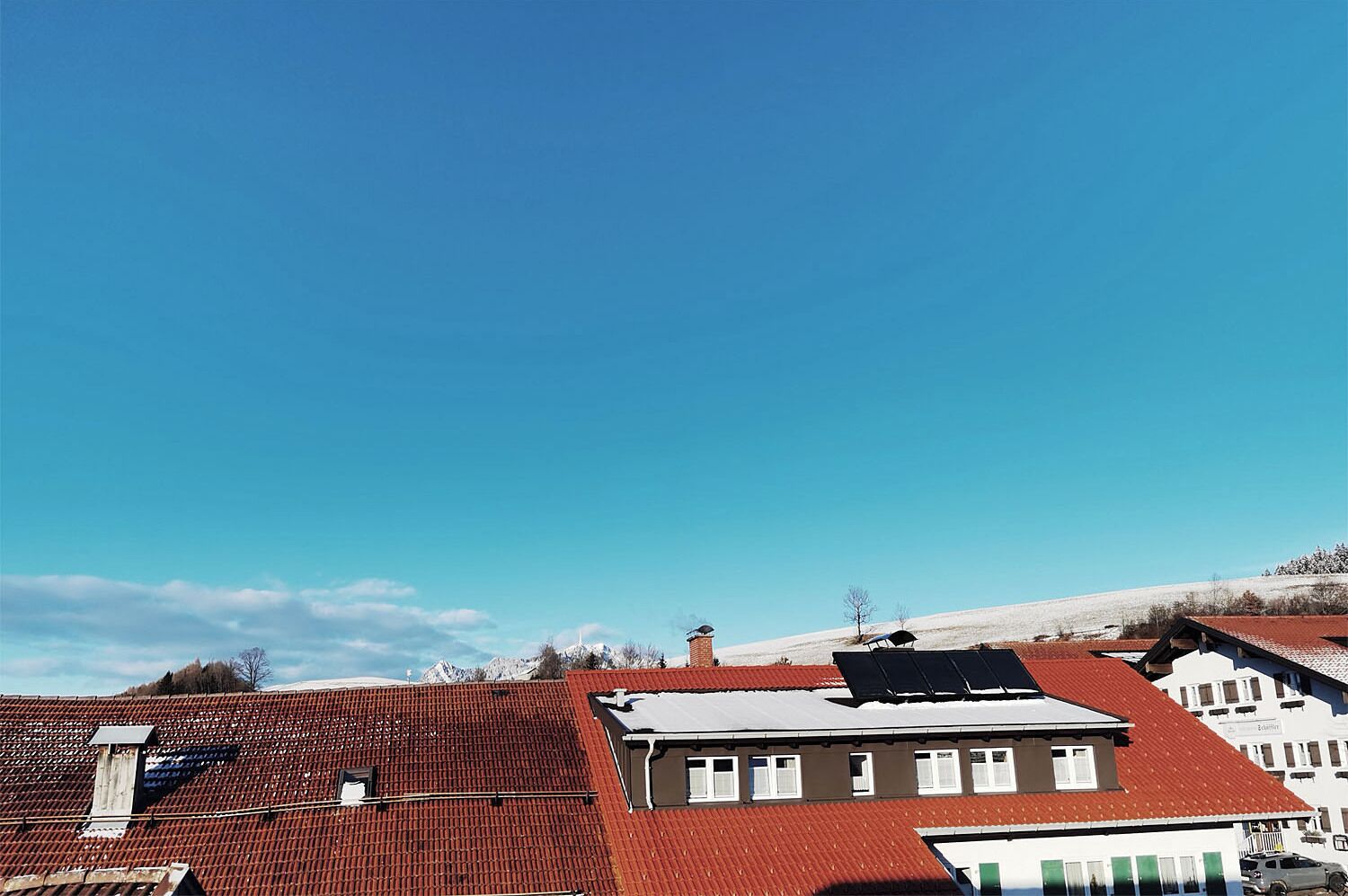 Zona residencial con tejados de tejas rojas y un cielo azul despejado.