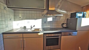 A modern kitchen with a stainless steel stove, oven, and dishwasher, a microwave, and a sink with a faucet. - Haus Rist - Apartment Panoramablick in Altstädten im Allgäu (Sonthofen)