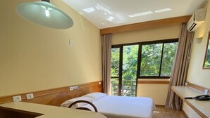 A hotel room with a bed, a desk, a chair, a round table, and a ceiling fan. - Hotel Canto da Ilha (Florianópolis)