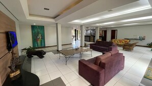A spacious living area with a large sofa, a coffee table, and a television mounted on the wall. - Hotel Canto da Ilha (Florianópolis)