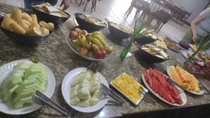 A buffet table with various fruits and vegetables, including bananas, apples, and carrots. - Hotel Canto da Ilha (Florianópolis)