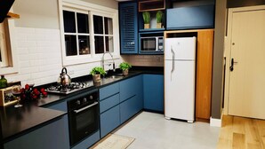 A modern kitchen with blue cabinets, a white refrigerator, a stove, and a microwave.