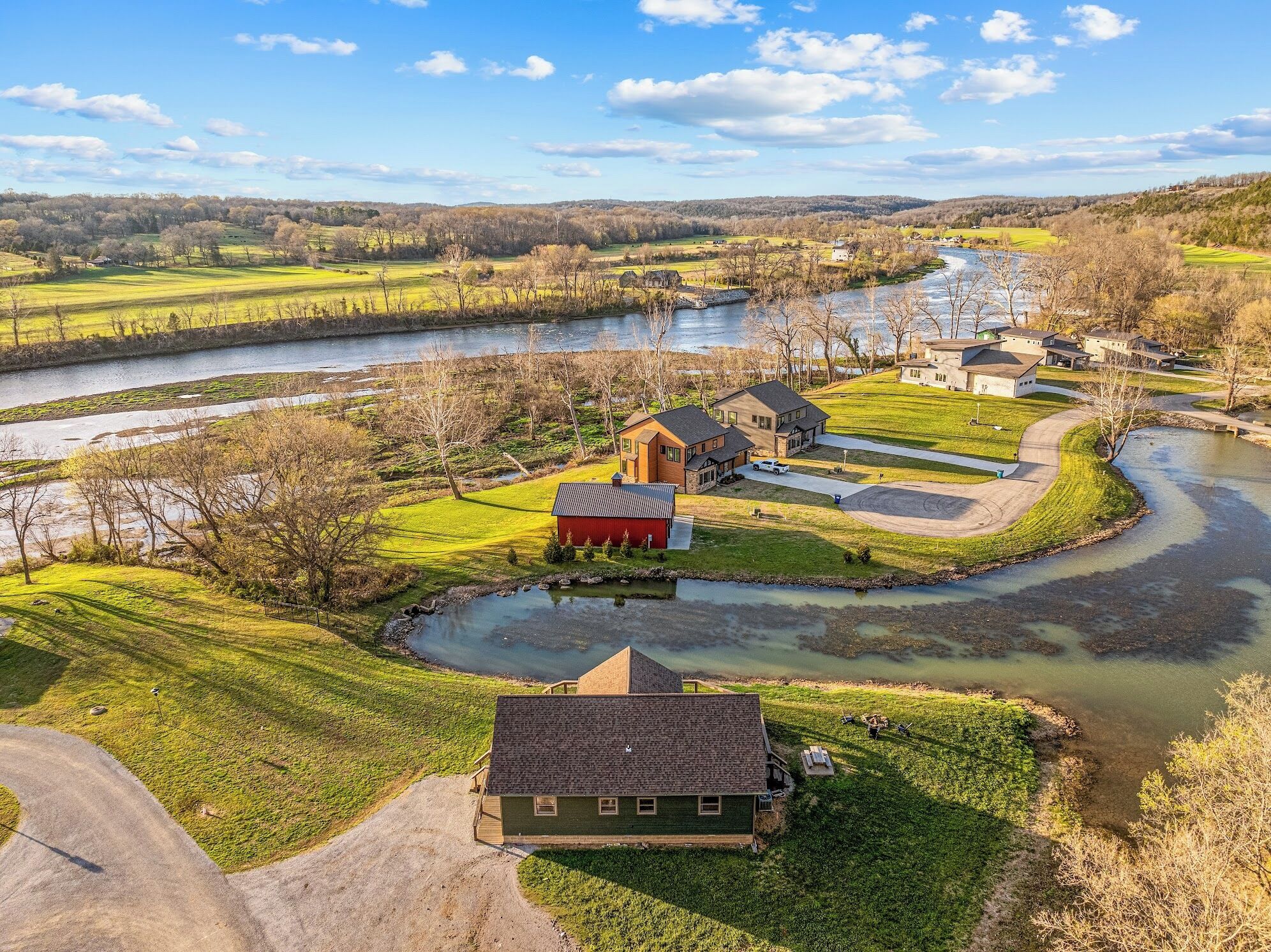 A rural landscape with a river, houses, and open fields.
