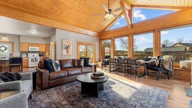 Un vaste espace de vie doté d’un plafond en bois, comprenant un coin repas et une cuisine.