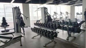 Een sportschool met diverse fitnessapparaten, waaronder loopbanden, krachttoestellen en gewichten.
