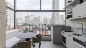 Una cucina moderna con un'ampia finestra, un'area pranzo con sedie e vista su edifici alti.