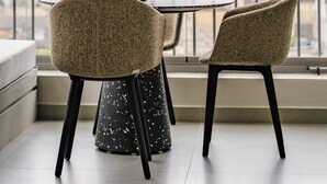 Un balcone con tavolo e sedie, una ciotola di mele verdi e vista su alti edifici.