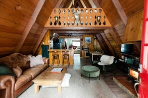 Cozy cabin interior with a leather sofa, wooden coffee table, and fireplace.