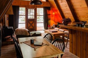 Work and unwind in this cabin's cozy dining area, featuring a comfortable seating space and a large window offering a scenic view.