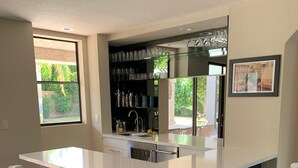Uma cozinha moderna com uma ilha central, banquetas e uma janela grande.